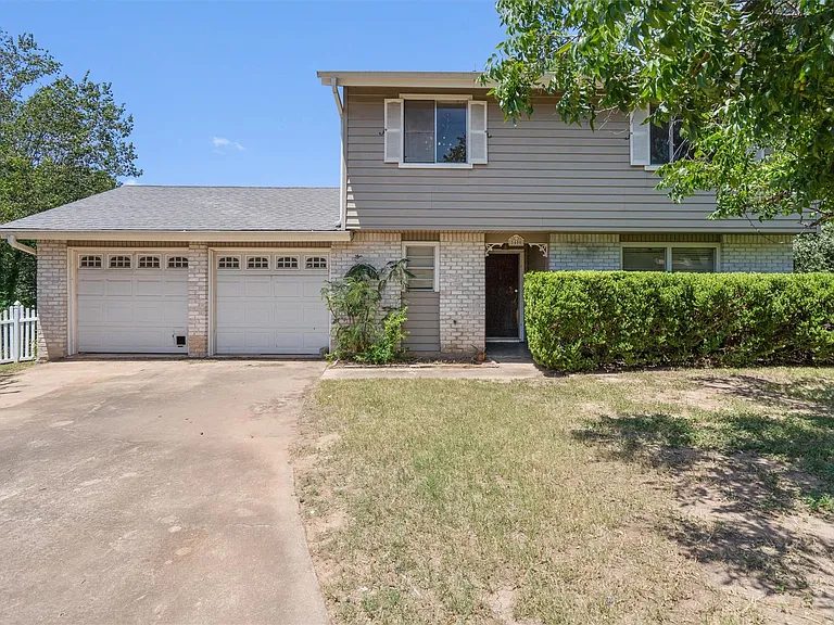 Before: original two-story home with dated gray siding and bare front yard
